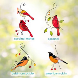 Decorative stained glass birds in vibrant colors, perched on elegant wire branches with leaves and berries, creating a nature-inspired wall or window display.