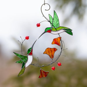 Stained glass green hummingbirds flying towards each other window hanging