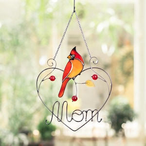 Handcrafted stained glass cardinal suncatcher with vibrant red and yellow flowers, displayed in a home interior.