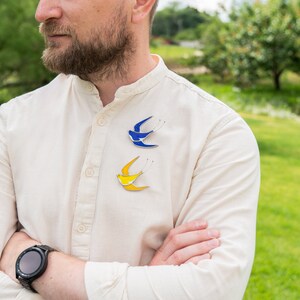 a men is wearing stained glass swallow brooches