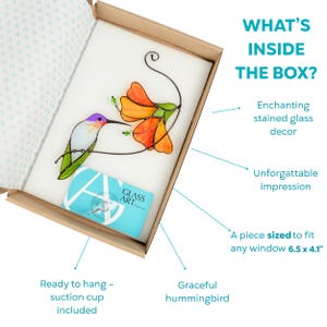 Open gift box with a stained glass hummingbird and orange flower suncatcher, suction cup and brand card included inside