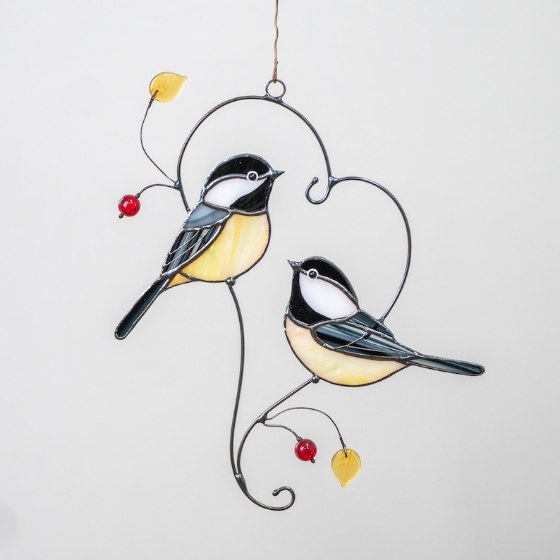 made of stained glass chickadees sitting on the branch with yellow leaves and red berries