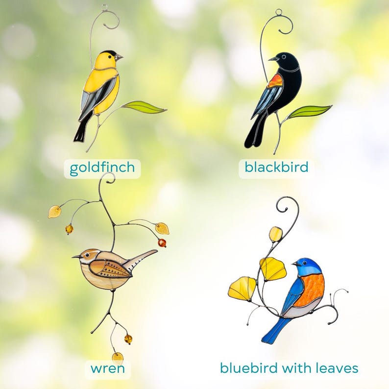 Collection of stained glass bird sun catchers including a goldfinch, blackbird, wren, and bluebird with leaves, arranged on elegant wire designs with a light green backdrop.