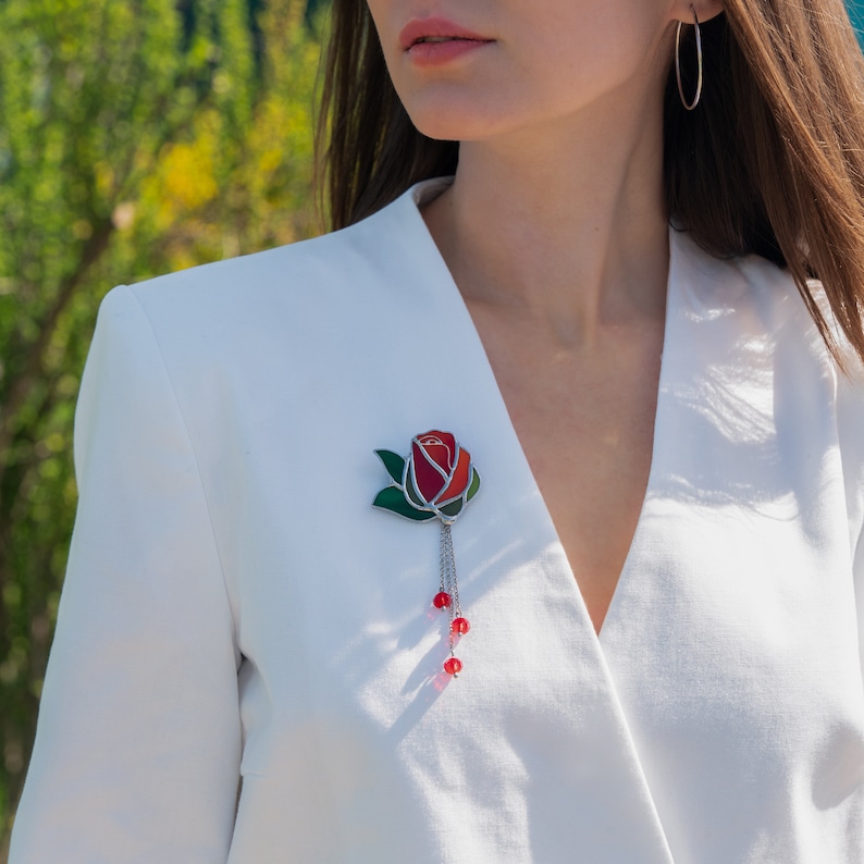 a girl wears the stained glass red rose pin on the white costume