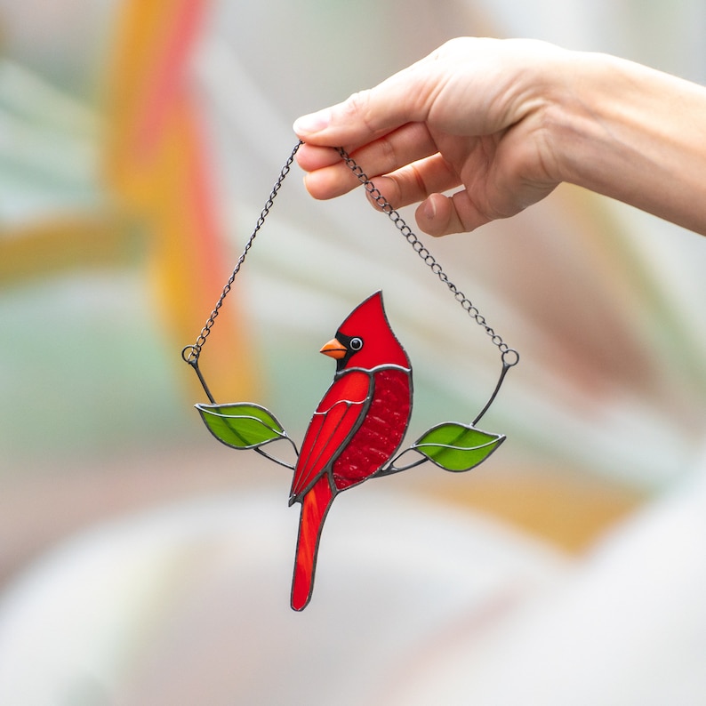 red cardinal made of stained glass sitting on the branch