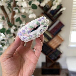 May include: A white, pink, green and purple fuzzy hair scrunchie.