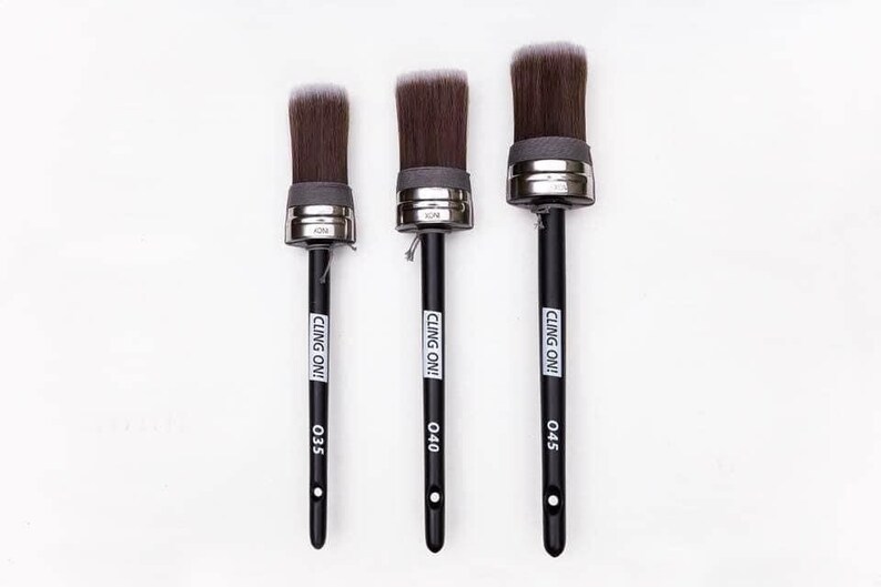 May include: Three round paint brushes with black handles and dark brown bristles. The brushes have silver metal ferrules and are labeled with the text "CLING ON!" and size numbers 035, 040, and 045. The background is white.