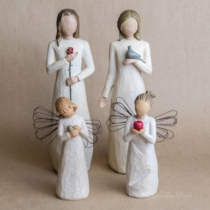 May include: Four white wooden angel figurines with wire wings. The angels are holding a red rose, a dove, a small bird, and a red apple.