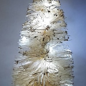 May include: A white, brush-like artificial Christmas tree with white lights and a brown wooden base.