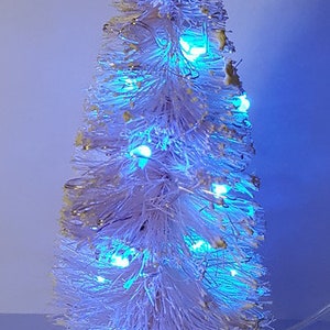 May include: A white artificial Christmas tree with blue LED lights. The tree is decorated with a string of lights that are wrapped around the branches.