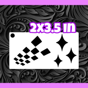 May include: A white stencil with two designs. The first design is a cluster of black squares arranged in a diagonal pattern. The second design is three black diamond shapes. The stencil measures 2 by 3.5 inches.