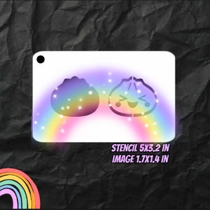 May include: A rectangular white stencil featuring two dumpling shapes, one solid and one with a smiling face, surrounded by a rainbow gradient and small star accents. The text STENCIL 5X3.2 IN and IMAGE 1.7X1.4 IN is printed in purple.