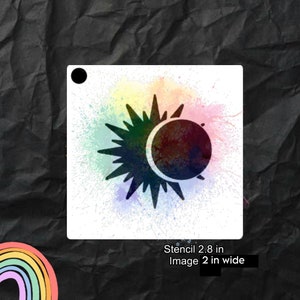 May include: A black and white stencil of a sun and moon with a rainbow watercolor background. The stencil is 2.8 inches wide and the image is 2 inches wide.