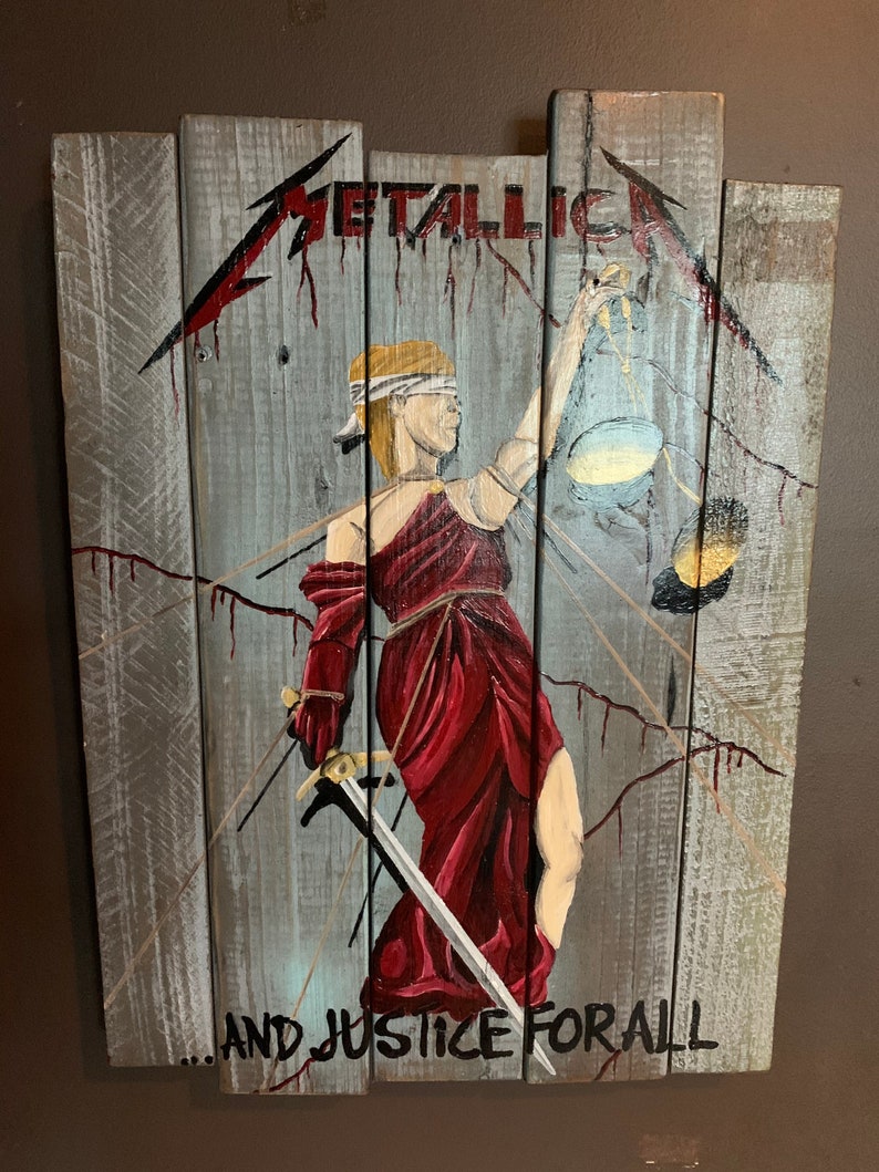 May include: A wooden sign with a painted image of a blindfolded figure holding a scale and sword. The text "METALLICA...AND JUSTICE FOR ALL" is painted on the sign.