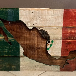 May include: A wooden sign in the shape of Mexico painted with the colors of the Mexican flag. The green, white, and red colors are painted on wooden planks. The sign is distressed and has a rustic look.