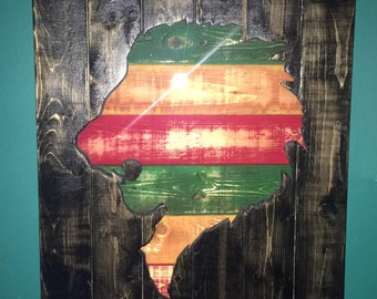 May include: A wooden wall art piece featuring a lion's head silhouette cut out of the wood. The lion's head is painted in a multi-colored striped pattern of green, red, yellow, and orange.