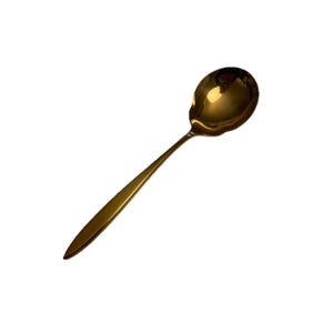 Pode incluir: Uma colher de servir dourada com uma tigela arredondada e um cabo longo e fino. A colher é feita de um metal brilhante e reflexivo, sobre um fundo branco. A colher foi projetada para servir alimentos.