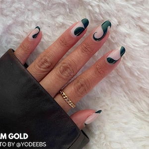 Peut inclure: Gros plan d'une main avec un vernis à ongles vert et blanc avec un motif en spirale. Les ongles sont de forme ovale. La main porte une bague en or. Le texte "3MM GOLD" et "PHOTO BY @YODEEBS" est en bas de l'image.