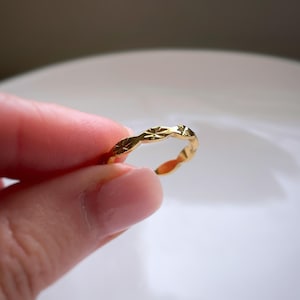 Peut inclure: Une bague dor&eacute;e pr&eacute;sentant une s&eacute;rie de motifs en &eacute;toile grav&eacute;s et r&eacute;p&eacute;t&eacute;s sur la bande ext&eacute;rieure. La surface m&eacute;tallique est polie et r&eacute;fl&eacute;chissante, avec un design &agrave; bords festonn&eacute;s qui suit le contour de chaque motif &eacute;toil&eacute;.