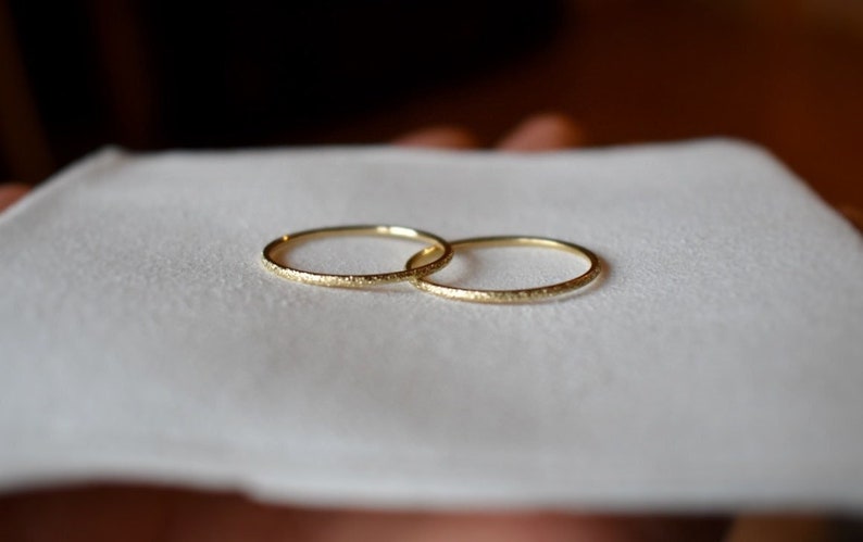 dainty, gold ring is 1 millimeter wide and features a sandblasted stardust finish