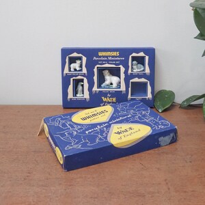 Peut inclure: Une boîte bleue avec une étiquette blanche et jaune qui dit "Whimsy's Porcelain Miniatures Set No. 6 Polar Set by Wade of England". La boîte contient un ensemble de six figurines miniatures en porcelaine d'animaux, dont un ours polaire, un ourson polaire, un manchot empereur, un bébé phoque et un husky.