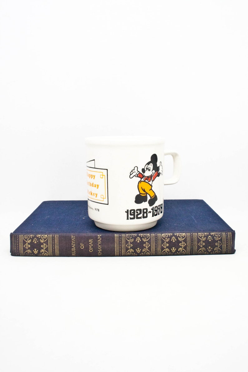May include: White ceramic mug featuring a cartoon image of Mickey Mouse and the text "Happy Birthday Mickey 1928-1978".