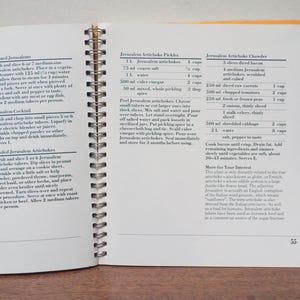 May include: Open cookbook with spiral binding, featuring recipes for Jerusalem artichokes. The pages display text with ingredient lists and instructions for various dishes, including pickles and chowder. The page number 55 is visible.