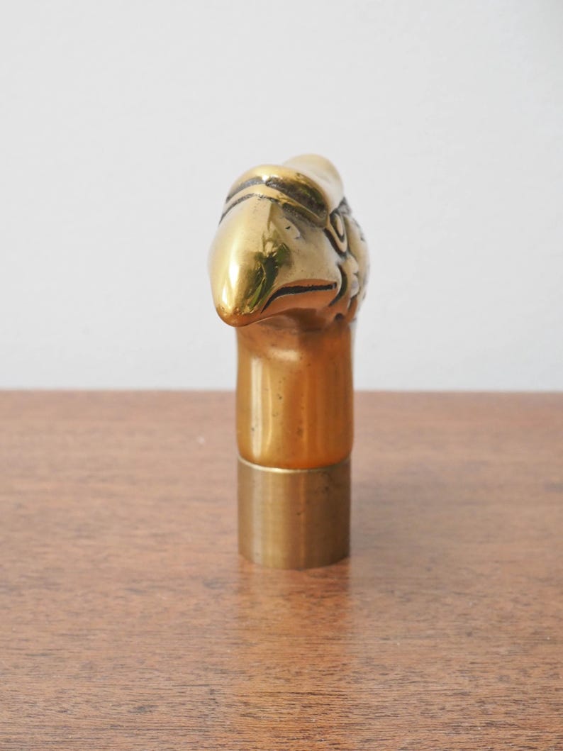Puede incluir: Un tap&oacute;n de botella de lat&oacute;n con un dise&ntilde;o detallado de cabeza de &aacute;guila. El tap&oacute;n tiene un acabado dorado pulido, con el pico y la cabeza del &aacute;guila claramente definidos. La base cil&iacute;ndrica tambi&eacute;n es de lat&oacute;n. Adecuado para botellas de vino.