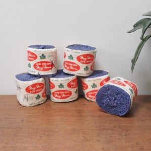 May include: Six spools of blue rug yarn with white labels that read "Mary Maxim Rug Wool" and "Laine Pour Tapis Mary Maxim".