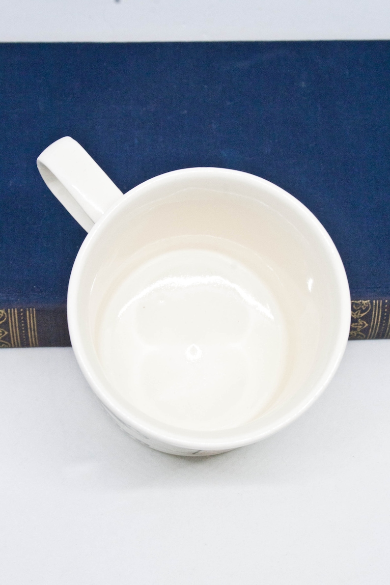 May include: White ceramic mug with a handle. The mug is empty and has a smooth, glossy finish.