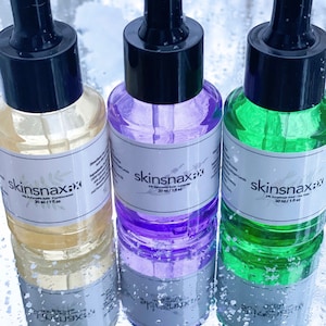 May include: Three glass bottles with dropper tops filled with different coloured liquids. The bottles are labelled "skinsnax" and contain 1% Hyaluronic Acid. The bottles are 30 ml / 1 fl oz.