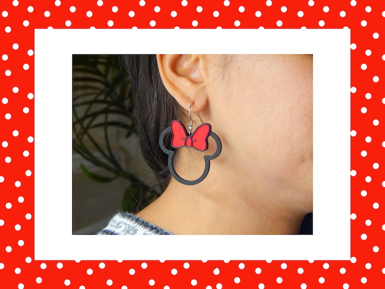 May include: Black Minnie Mouse-shaped earrings with a red bow. These earrings are a playful accessory, ideal for fans of the famous character. The earrings are lightweight and easy to wear, adding a touch of fun to any outfit.