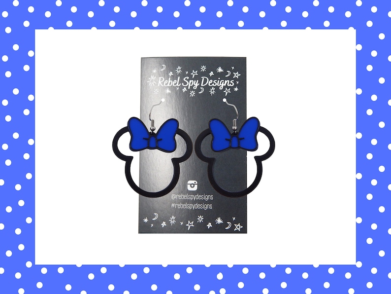May include: Black outline Minnie Mouse head earrings with a blue bow. The earrings are displayed on a silver card with the text "Rebel Spy Designs" and social media handles. The background is white with a blue polka dot border.
