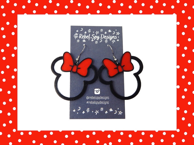 May include: Black and red Minnie Mouse-shaped earrings with red bows. The earrings are on a dark blue card with the text "Rebel Spy Designs" and social media handles. The background is white with a red polka dot border.