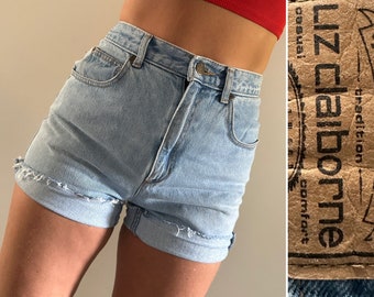 Puede incluir: Pantalones cortos de mezclilla azul claro con dobladillo deshilachado y pierna remangada. Los pantalones cortos tienen cintura alta y un ajuste holgado. La etiqueta en los pantalones cortos dice "Liz Claiborne - tradición - comodidad - casual."