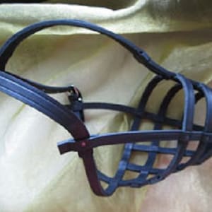 May include: A black plastic dog muzzle with a wire cage design. The muzzle is designed to prevent a dog from biting.