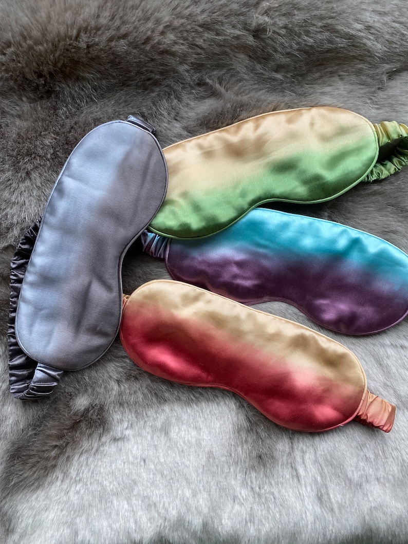 May include: Four silk sleep masks in different ombre colors. The masks are gray, green, blue, and red.