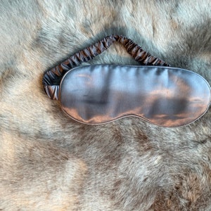 May include: A gray silk sleep mask with an elastic band.