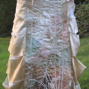 May include: A white wedding dress with a layered skirt and intricate embroidery. The skirt is made of different fabrics and textures, creating a unique and bohemian look.