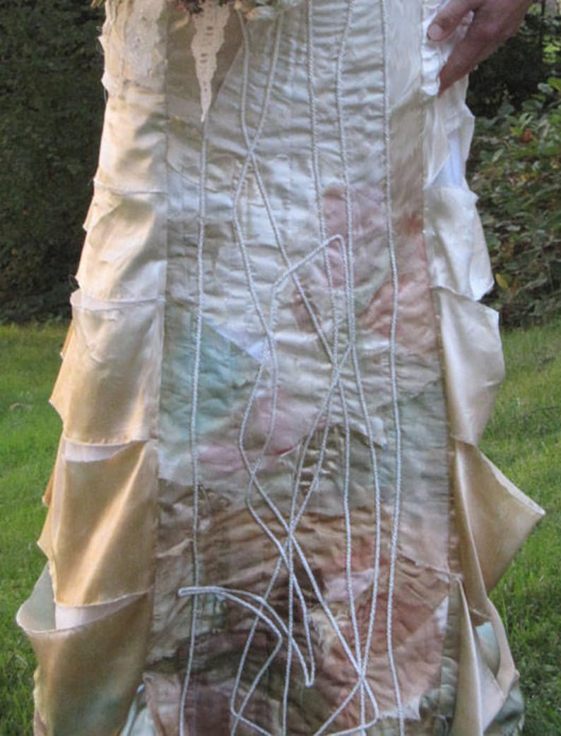 May include: A white wedding dress with a layered skirt and intricate embroidery. The skirt is made of different fabrics and textures, creating a unique and bohemian look.