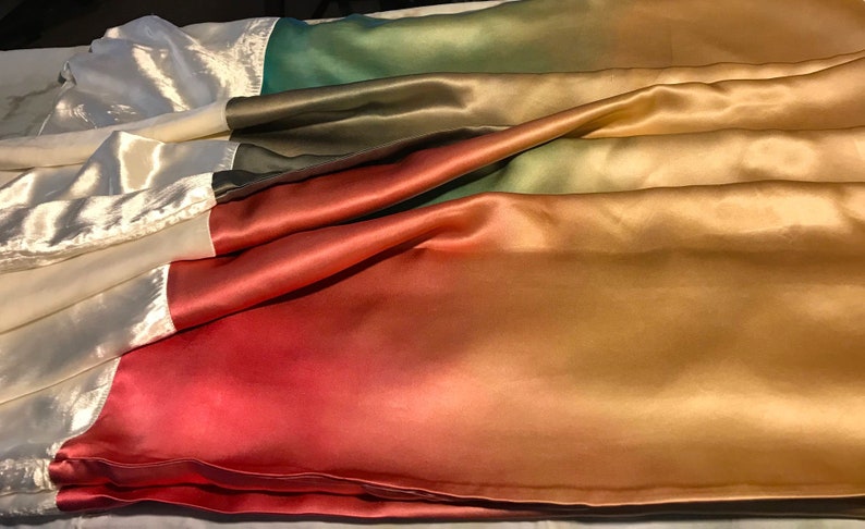 May include: A gradient fabric with a white, green, red, orange, and gold color scheme. The fabric is made of satin and has a smooth, silky texture.