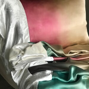 May include: A pile of different colored silk fabrics, including white, green, brown, and pink. The fabrics are arranged in a way that creates a gradient effect.