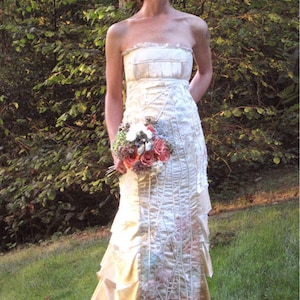 May include: A white strapless wedding dress with a layered skirt and a delicate floral pattern. The dress is made of a soft, flowing fabric and has a romantic, ethereal feel.