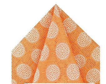 May include: Orange fabric with a white lace pattern of circles. The fabric has a textured, woven look.