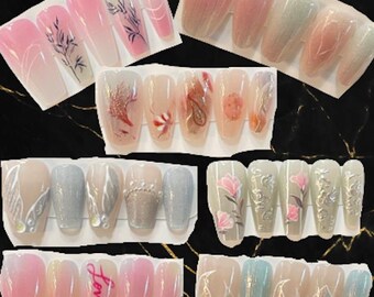 May include: A collection of long, opalescent nail designs. The designs include floral patterns, abstract art, and the word "Lover" on a pink background. Colors include pink, white, blue, and silver.