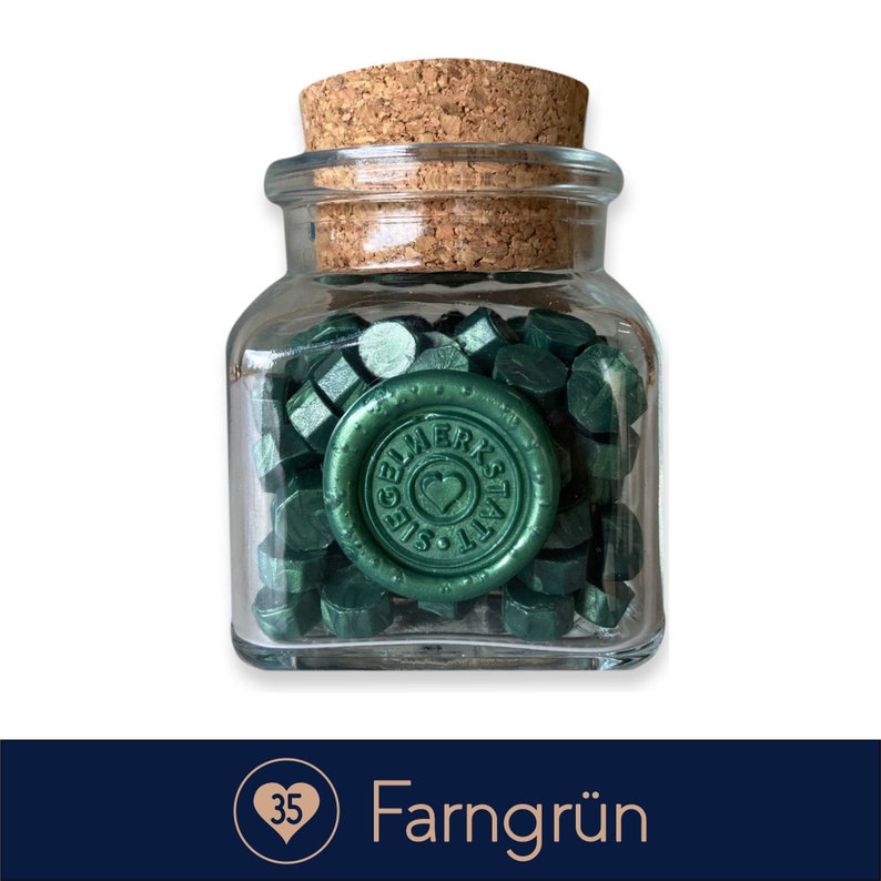May include: A glass jar filled with green sealing wax pellets. The jar has a cork lid and a label that says "Siegelwerkstatt".