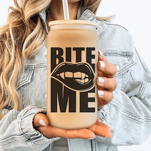 May include: A brown reusable tumbler with a black and white graphic of a mouth with fangs and the text "Bite Me".