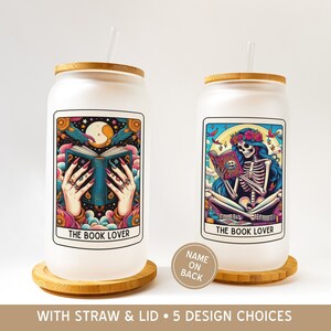 May include: Two white glass tumblers with bamboo lids and straws. Each tumbler features a colorful tarot card design with the text "THE BOOK LOVER." One design shows hands holding a book, the other a skeleton reading. The text "WITH STRAW & LID • 5 DESIGN CHOICES" is at the bottom.