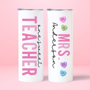 May include: Two white stainless steel tumblers with pink and black text. One tumbler says "Teacher" with a pink ombre effect and "One Sweet" written in cursive. The other tumbler says "Mrs. Anderson" with pink hearts that say "You Shine", "Ur Nice", "Awe Some", and "You Rock".