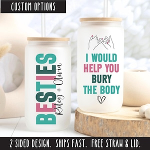 May include: Two white tumblers with lids and straws. One tumbler has the text "BESTIES Riley + Olivia" in teal, pink, and black. The other tumbler has the text "I WOULD HELP YOU BURY THE BODY" in teal, pink, and black with a heart at the bottom.